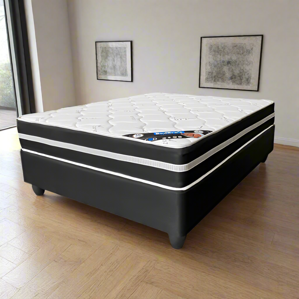 Black and white mattress on a wooden floor with framed pictures on the wall.