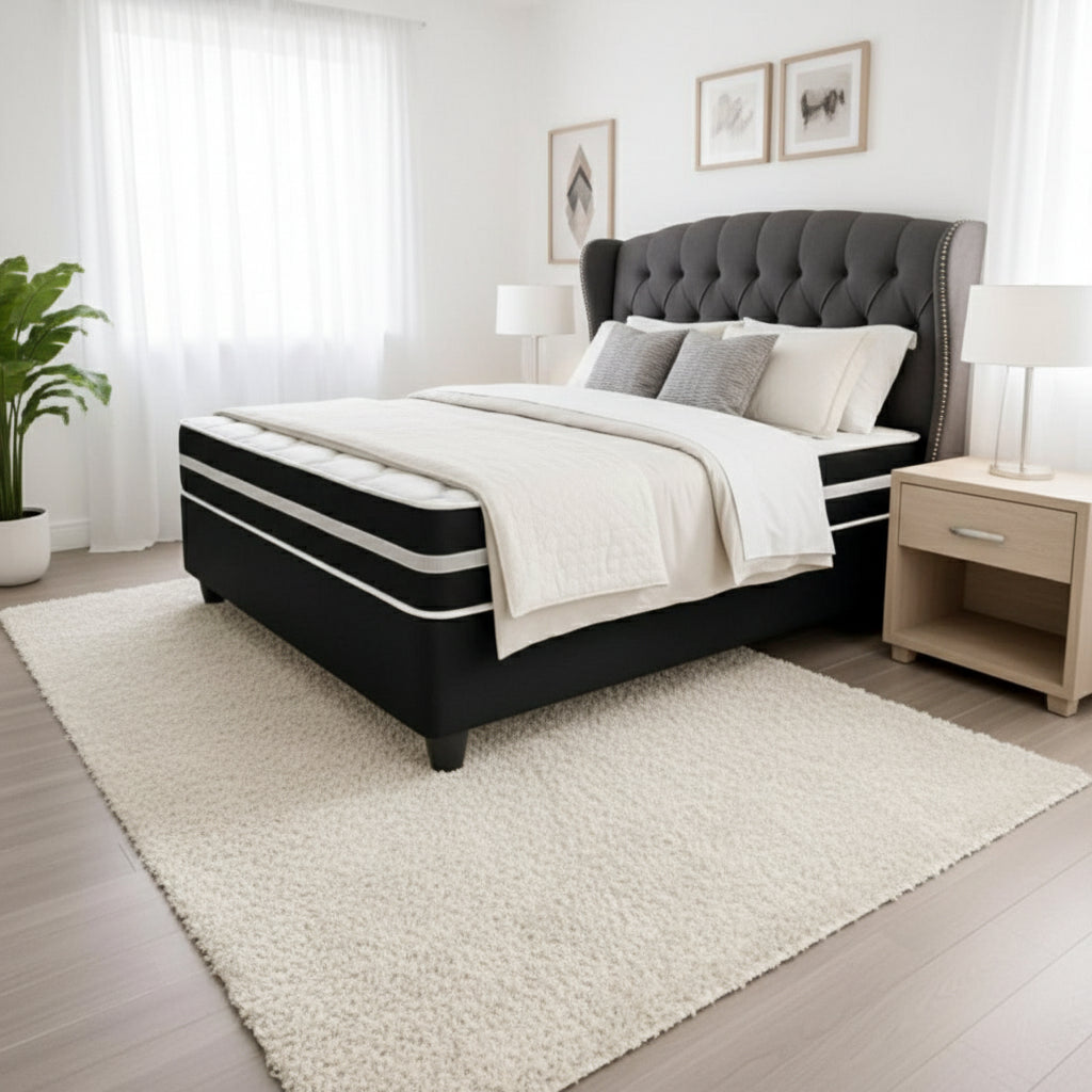 Black and white mattress on a wooden floor with a chair and rug in the background