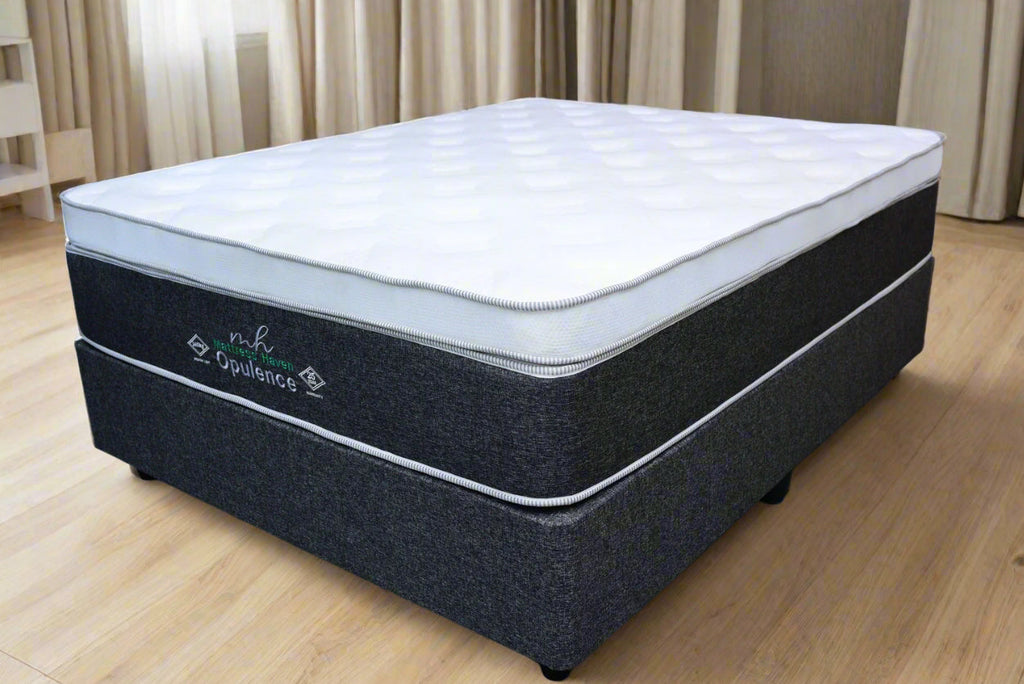 Mattress with 'Opulence' branding on a gray floor against a brick wall.