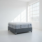 Two mattresses stacked on a gray floor with a neutral background