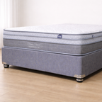 Gray mattress on a wooden floor with a white wall background