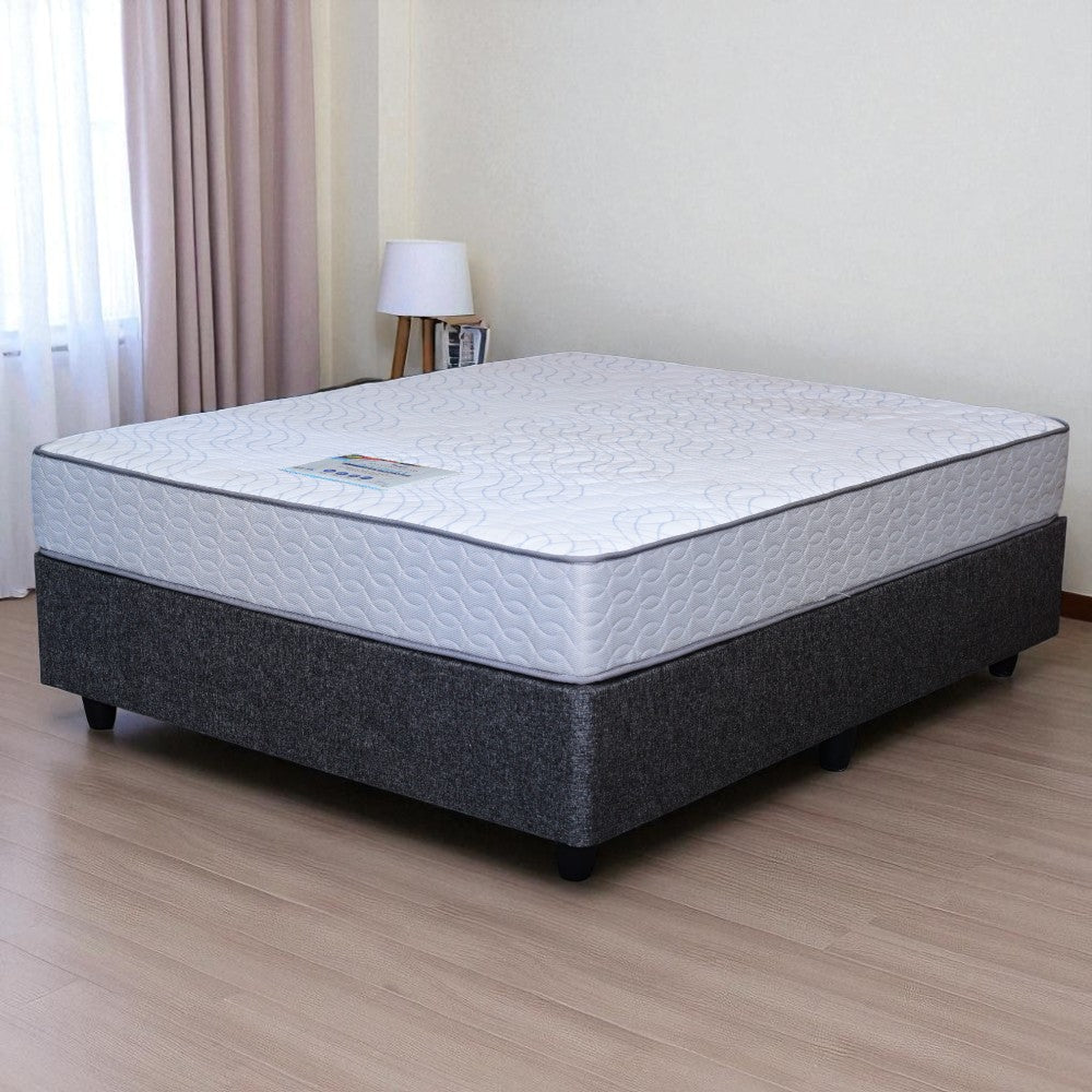 Mattress on a bed frame in a room with curtains and a lamp.