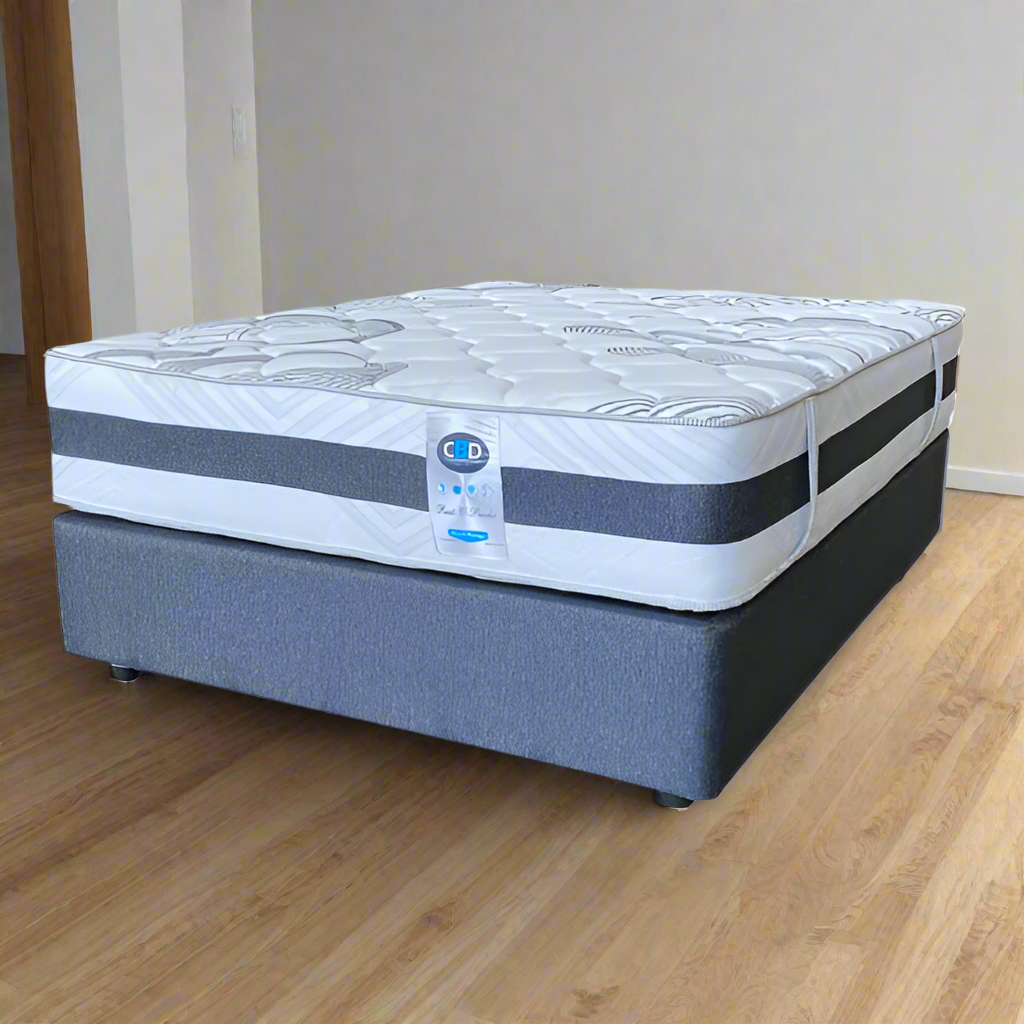 A queen-sized mattress with a patterned white and blue cover on a gray bed frame.
